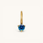 Nadare Co. mini birthstone charm featuring a round-cut blue gemstone set in polished gold on a small hoop.