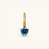 Nadare Co. mini birthstone charm featuring a round-cut blue gemstone set in polished gold on a small hoop.