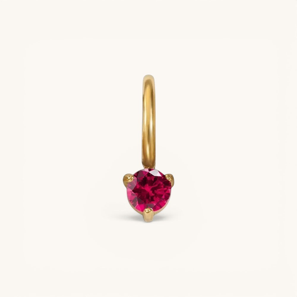 Nadare Co. mini birthstone charm featuring a round-cut vibrant red gemstone set in polished gold.