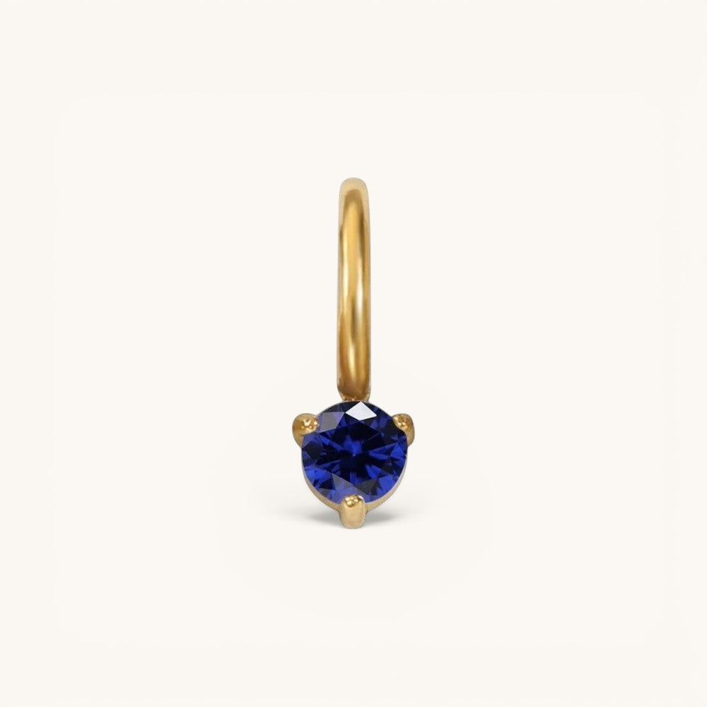 Nadare Co. mini gold hoop charm featuring a round-cut blue sapphire birthstone in a three-prong setting.