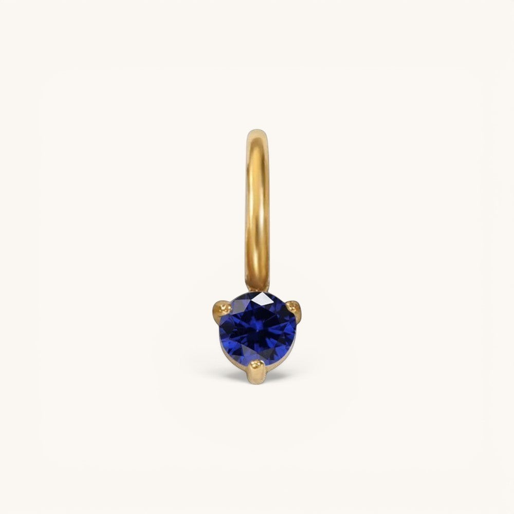 Nadare Co. mini gold hoop charm featuring a round-cut blue sapphire birthstone in a three-prong setting.