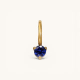 Nadare Co. mini gold hoop charm featuring a round-cut blue sapphire birthstone in a three-prong setting.