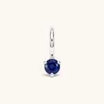 Nadare Co. mini birthstone charm featuring a round blue cubic zirconia stone set in silver-toned stainless steel.