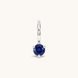 Nadare Co. mini birthstone charm featuring a round blue cubic zirconia stone set in silver-toned stainless steel.