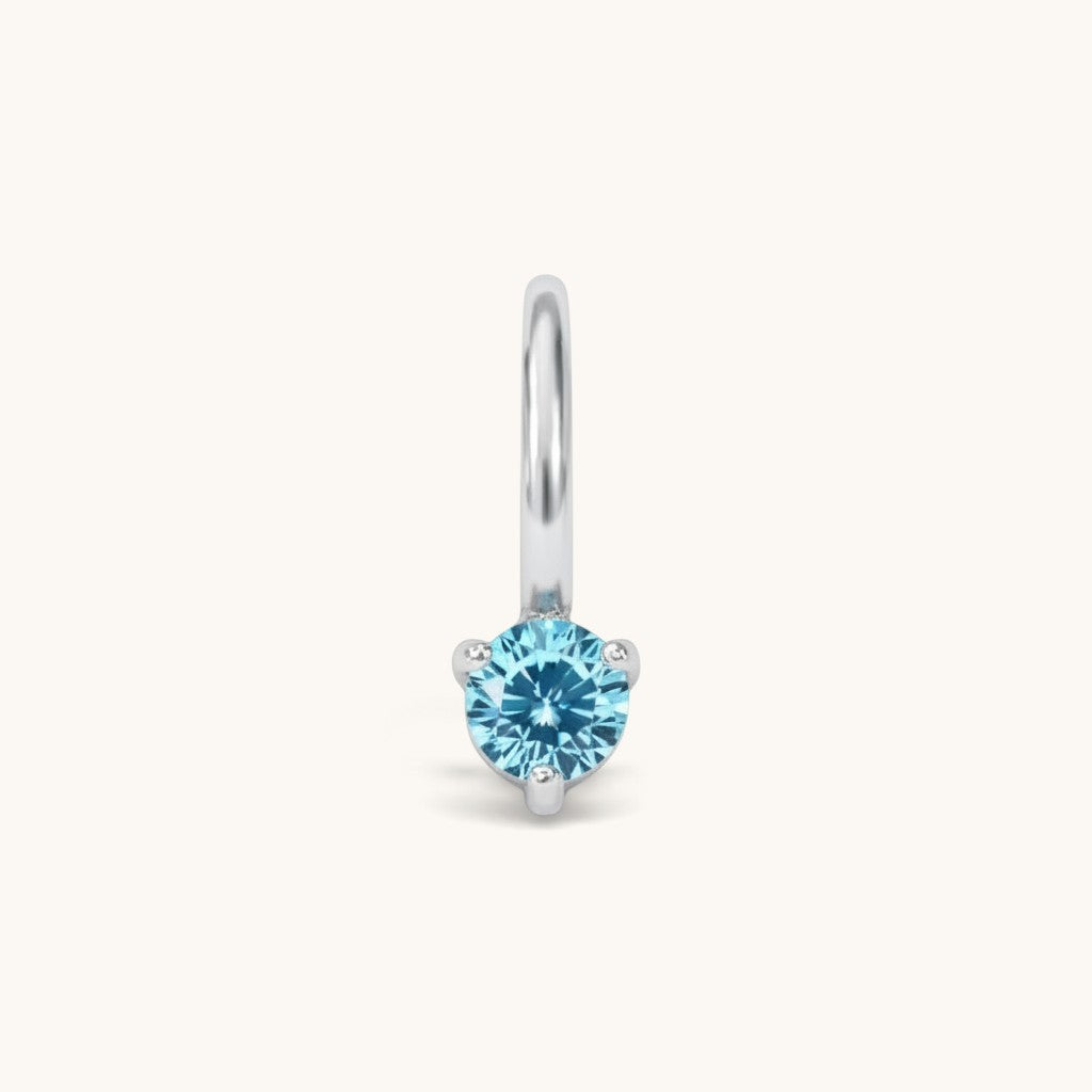 Nadare Co. mini birthstone charm in silver with a round light blue cubic zirconia stone for necklace layering.