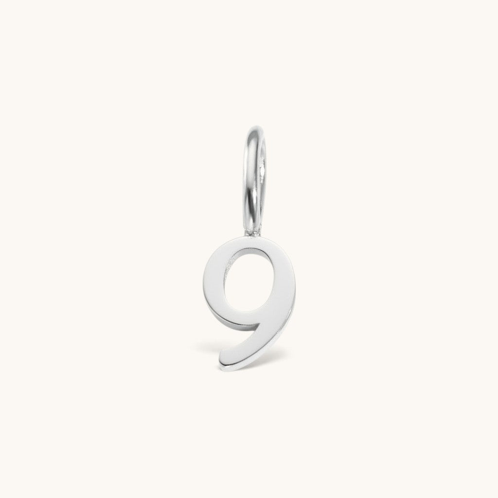 Nadare Co. number 9 charm in silver-toned stainless steel for minimalist jewelry layering.