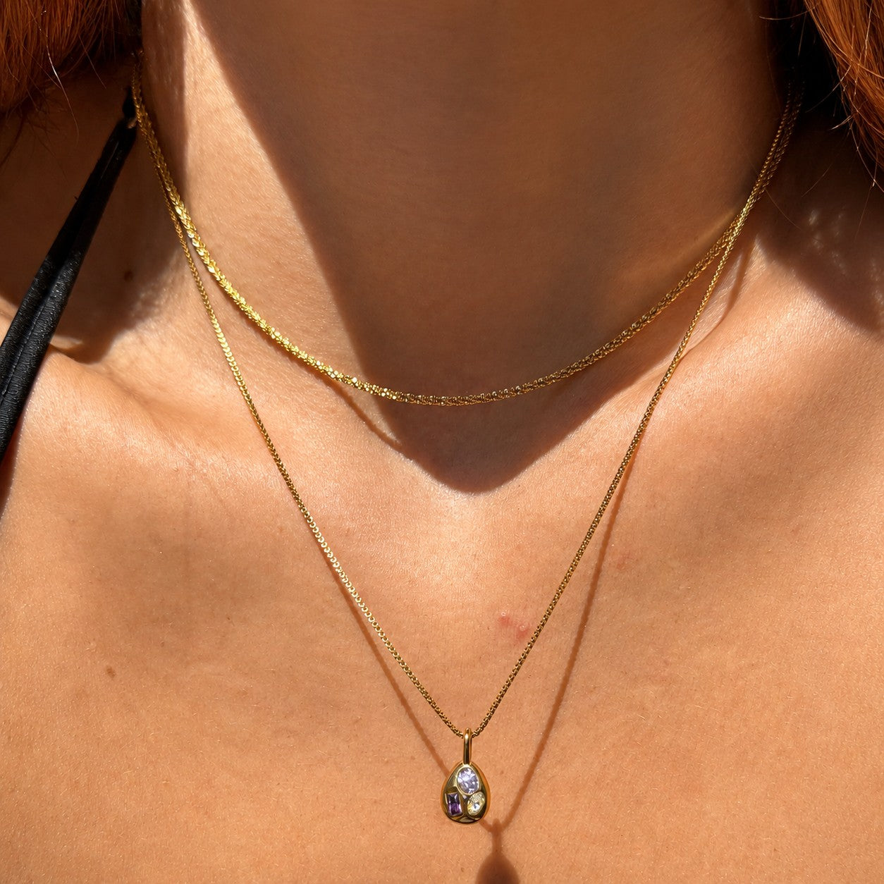 Nadare Co. Paloma Necklace featuring a gold box chain and a sculptural pendant with three mismatched colorful stones.