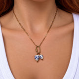 Nadare Co. gold chain necklace featuring two oval porcelain beads with blue floral patterns and gold accents.
