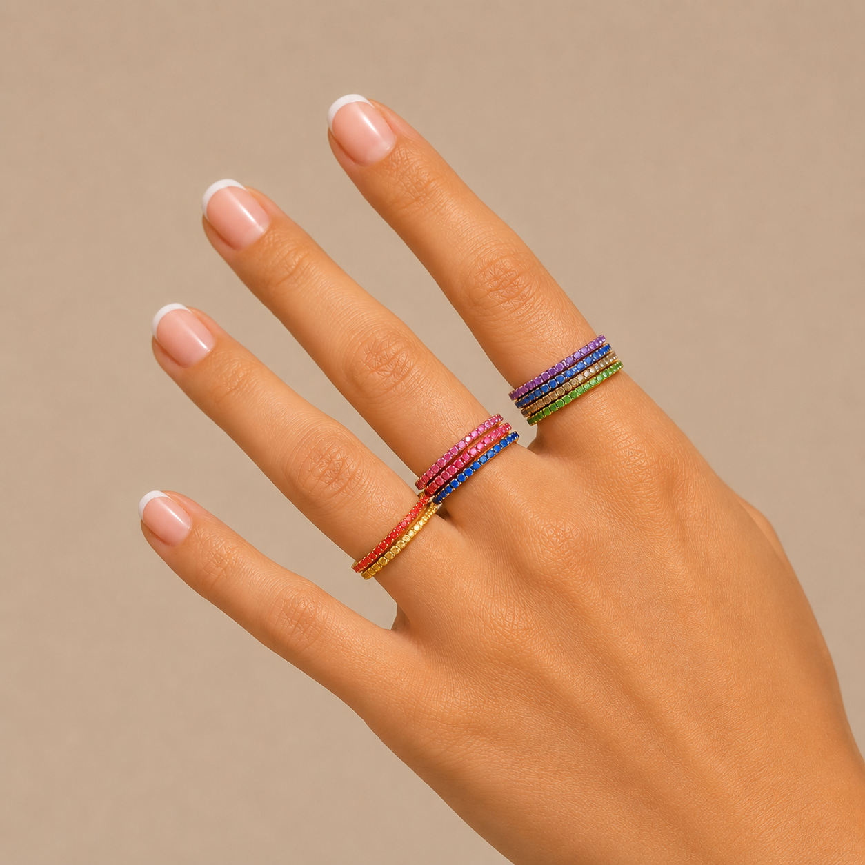 Nadare Co. Prism Birthstone rings in various vibrant colors stacked on a woman's fingers against a neutral background.