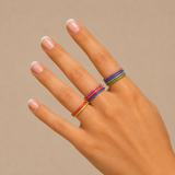 Nadare Co. Prism Birthstone rings in various vibrant colors stacked on a woman's fingers against a neutral background.