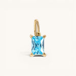 Nadare Co. rectangle birthstone charm featuring a bright blue gemstone set in polished gold on a small jump ring.