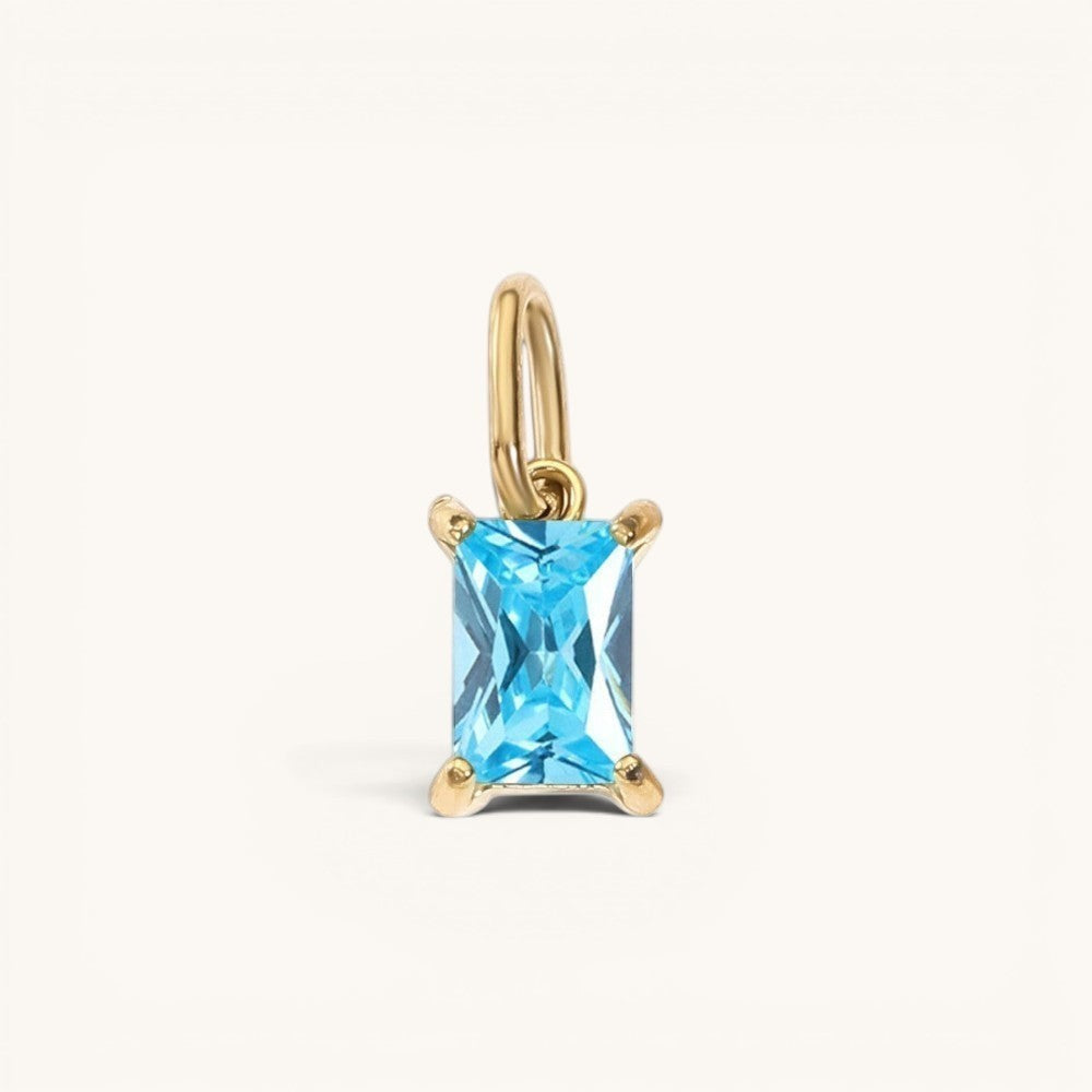 Nadare Co. rectangle birthstone charm featuring a bright blue gemstone set in polished gold on a small jump ring.