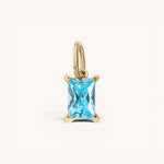 Nadare Co. rectangle birthstone charm featuring a bright blue gemstone set in polished gold on a small jump ring.