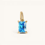 Nadare Co. rectangle birthstone charm featuring a vibrant blue gemstone set in polished gold.