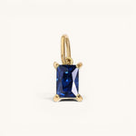 Nadare Co. rectangle birthstone charm featuring a deep blue sapphire-style gemstone set in polished yellow gold.