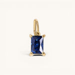 Nadare Co. rectangle birthstone charm featuring a deep blue sapphire-style gemstone set in polished yellow gold.