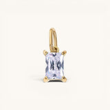 Nadare Co. rectangle birthstone charm featuring a clear emerald-cut crystal set in polished gold.
