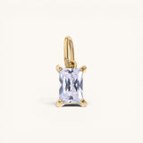Nadare Co. rectangle birthstone charm featuring a clear emerald-cut crystal set in polished gold.