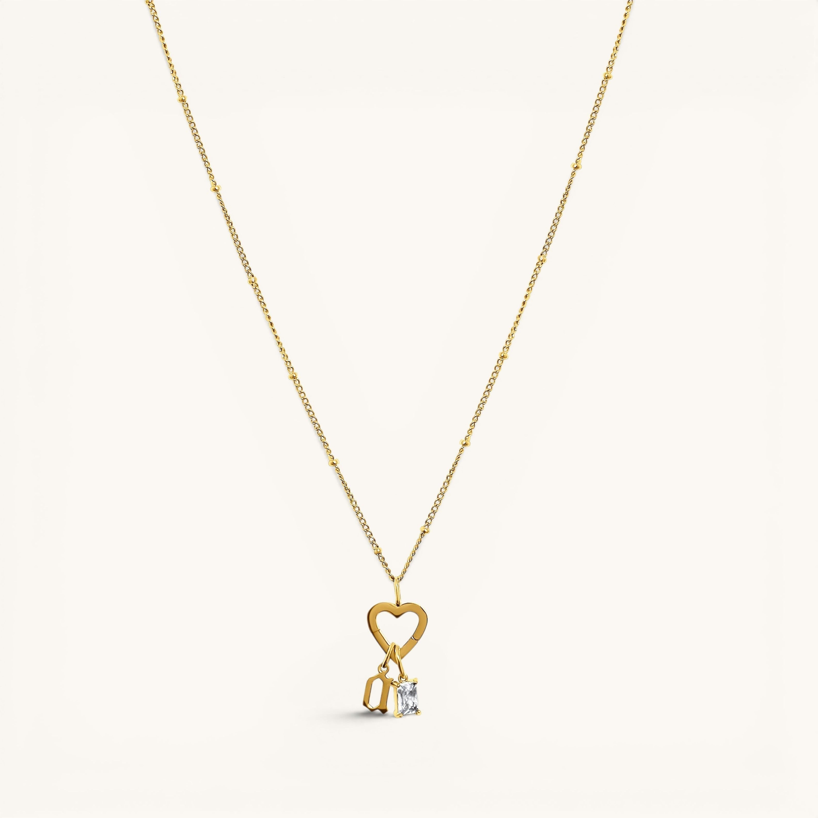 Nadare Co. gold necklace featuring a heart-shaped clasp charm with a dangling rectangle birthstone and letter charm.
