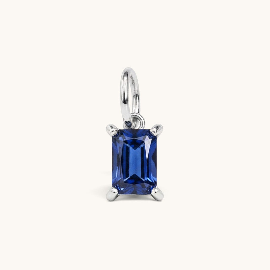 Nadare Co. rectangle birthstone charm featuring a deep blue cubic zirconia stone in a polished silver-tone setting.