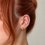 Nadare Co. Remi earrings featuring a chunky, sculptural gold teardrop design worn on a woman with red hair.