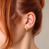 Nadare Co. Romi earrings featuring a chunky, twisted gold hoop design worn on a woman's ear.