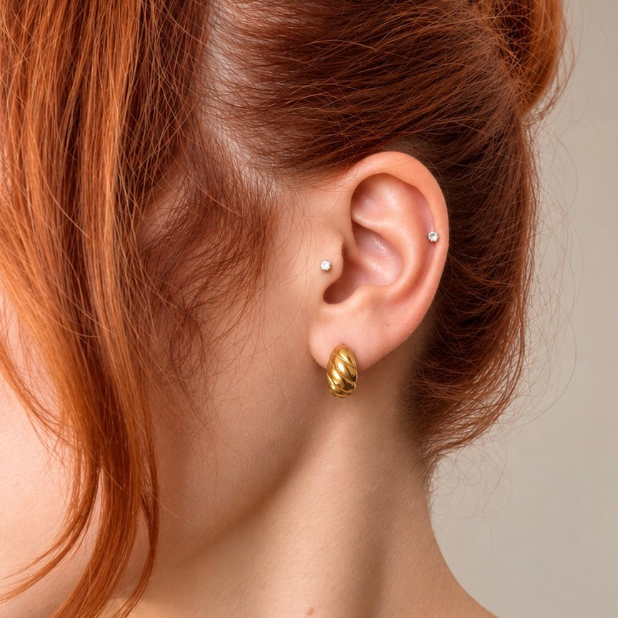 Nadare Co. Romi earrings featuring a chunky, twisted gold hoop design worn on a woman's ear.
