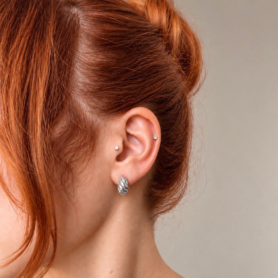 Nadare Co. Romi Earrings featuring a chunky, sculptural twisted silver hoop design worn on a model's earlobe.