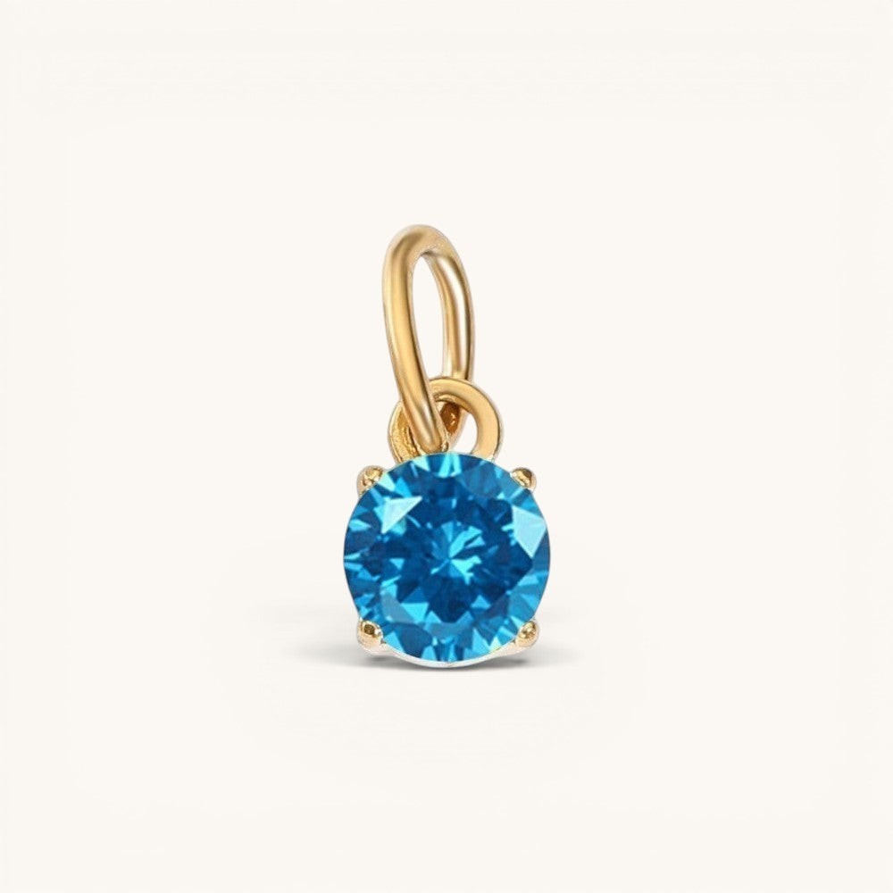 Nadare Co. round birthstone charm in 14k gold plated stainless steel with a bright blue cubic zirconia stone.