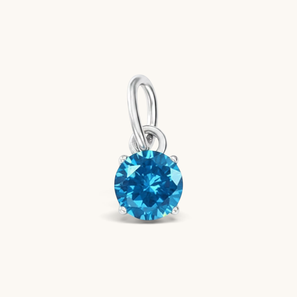 Nadare Co. round birthstone charm featuring a vibrant blue cubic zirconia stone in a silver-tone setting.