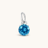 Nadare Co. round birthstone charm featuring a vibrant blue cubic zirconia stone in a silver-tone setting.