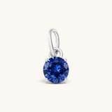 Nadare Co. round blue birthstone charm featuring a sparkling cubic zirconia stone set in polished silver-tone metal.