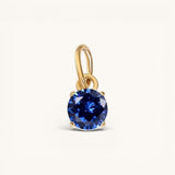 Nadare Co. round birthstone charm featuring a brilliant-cut deep blue gemstone set in polished yellow gold.