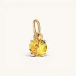 Nadare Co. round yellow birthstone charm in a gold prong setting, perfect for a delicate necklace pendant.