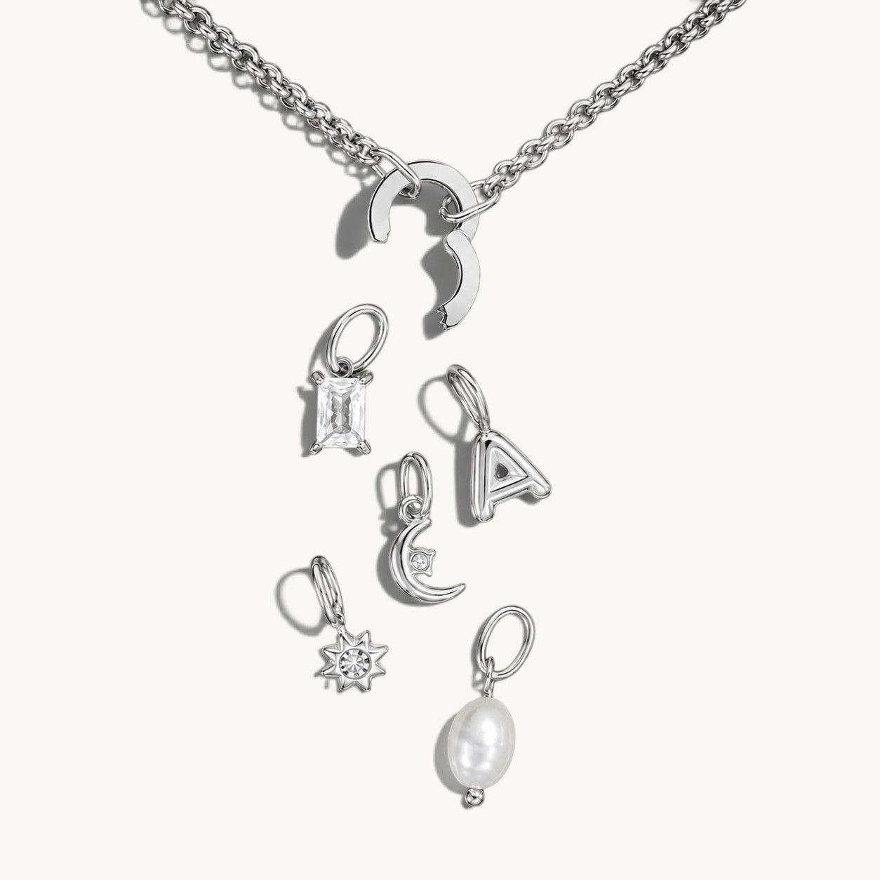 Nadare Co. silver chain necklace with a customizable clasp and various charms including a crystal, letter, and pearl.