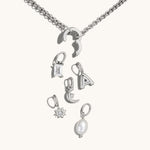Nadare Co. silver chain necklace with a customizable clasp and various charms including a crystal, letter, and pearl.