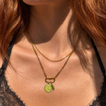 Nadare Co. Sylvie gold layered necklace with a curb chain, delicate chain, and a lemon charm on a carabiner clasp
