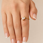 Nadare Co. Vela Birthstone Ring featuring a trillion-cut stone on a gold-plated open band worn on a finger.