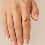 Nadare Co. Vela Birthstone Ring featuring a trillion-cut stone on a gold-plated open band worn on a finger.