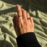 Nadare Co. Vela Birthstone Rings featuring trillion-cut stones on gold stainless steel open bands worn on a hand.