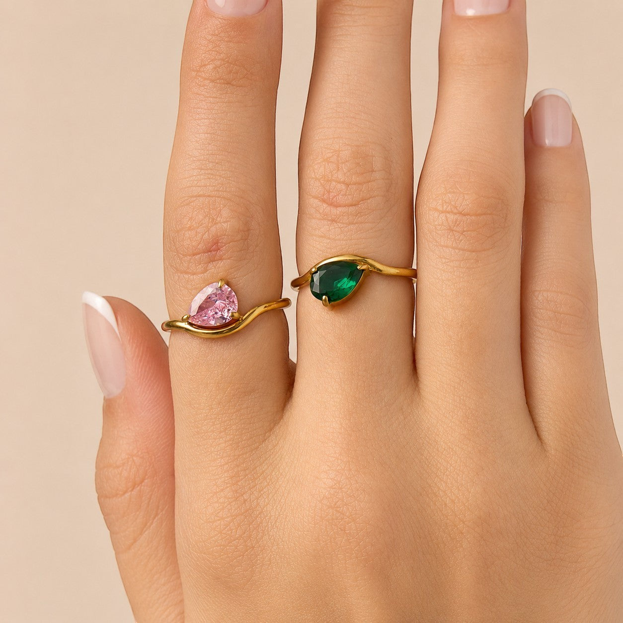 Nadare Co. Vela Birthstone Rings featuring pink and green trillion-cut stones on gold stainless steel open bands.