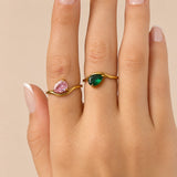 Nadare Co. Vela Birthstone Rings featuring pink and green trillion-cut stones on gold stainless steel open bands.